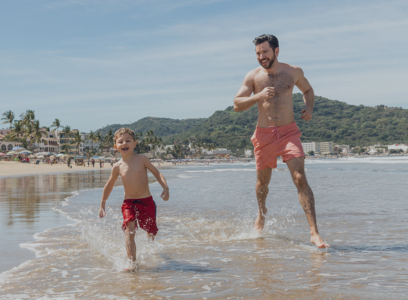 padre-juega-con-su-hijo-al-borde-de-la-playa-en-vacaciones-dia-soleado